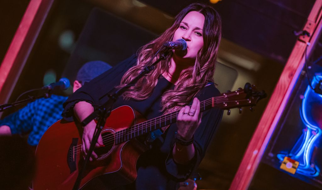 Amanda Grace performing live with red guitar under stage lights