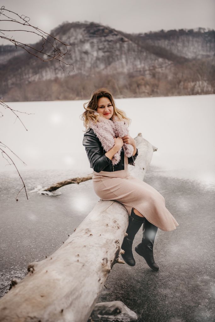 Amanda Grace sitting on a log by a frozen lake in winter