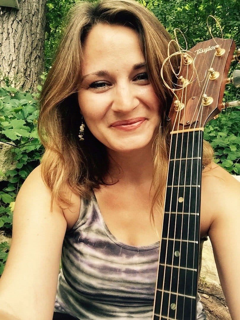 Amanda Grace outdoors with Taylor guitar, smiling